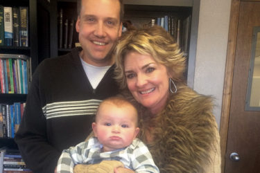 Family smiling in front of bookshelf