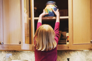Girl taking treats out of cabinet