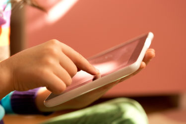 Child's hand playing on tablet