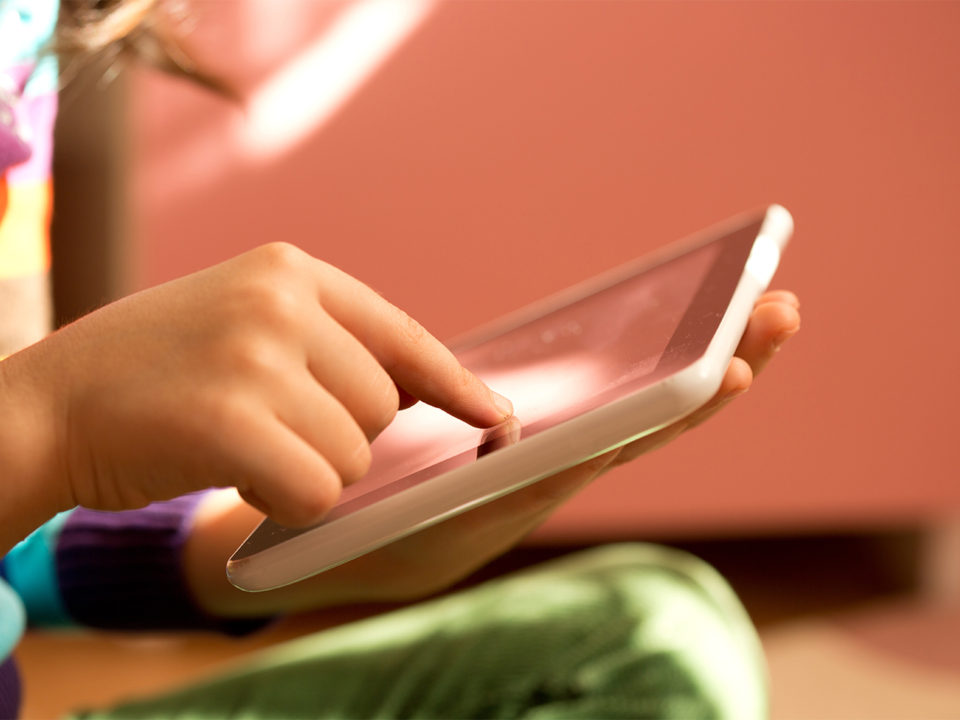 Child's hand playing on tablet