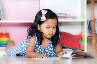 Little girl reading on floor