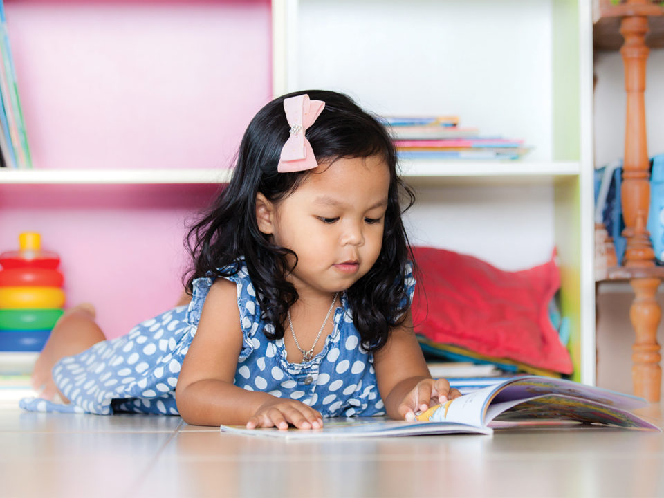 Little girl reading on floor