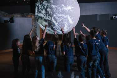 Group of children touching globe at CU South Denver