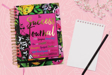 Journal, notebook and pencil on pink background