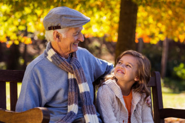 Grandfather sitting with granddaughter at park