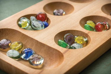 Traditional Mancala boardgame with glass pieces on wooden table