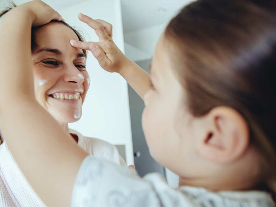Daughter putting lotion on mother's face