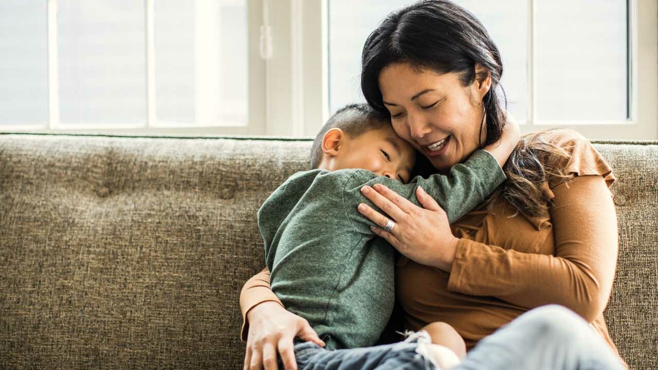 Mother hugging child on a couch
