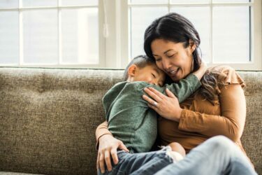 Mother hugging child on a couch