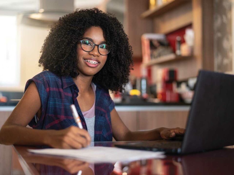 Teen writing, sitting at computer