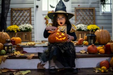 Girl in witch costume on front porch