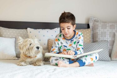 Boy reading to dog in bed
