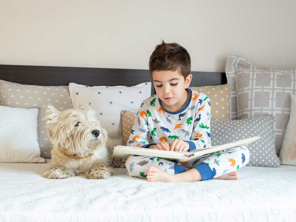 Boy reading to dog in bed