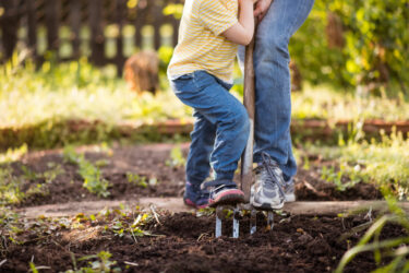 Child and parent with pitchfork in the garden
