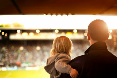 Parent holding toddler in sporting stadium