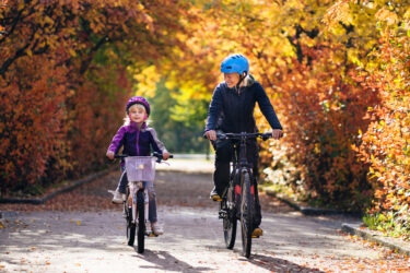 Parent and child rIding bikes in fall leaves