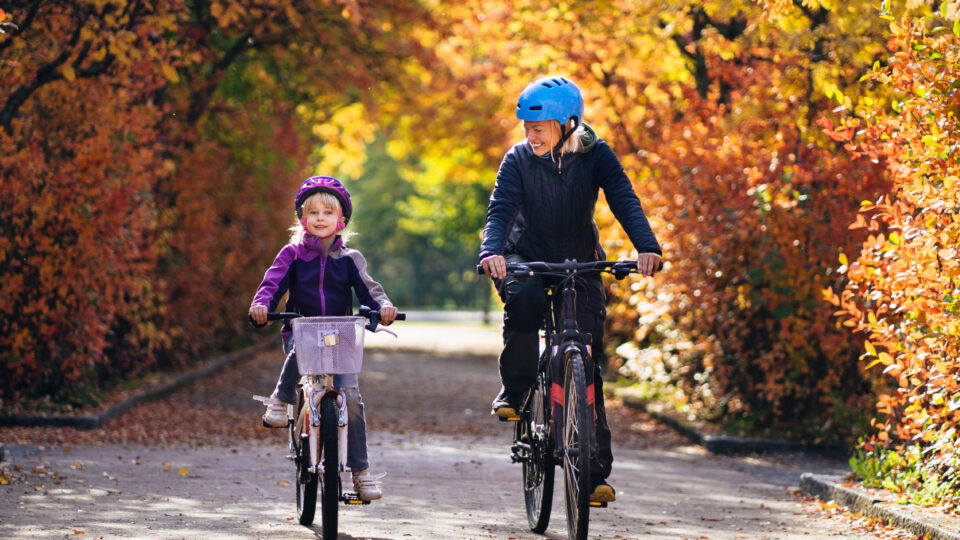 Parent and child rIding bikes in fall leaves