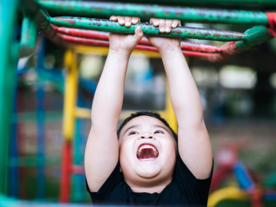 kid handing from monkey bars at a gym